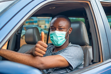 african driver wearing a face mask, doing the thumbs up gesture