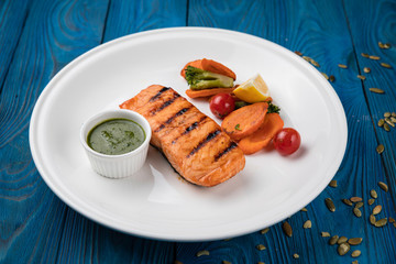 Grilled salmon with vegetables on a white plate
