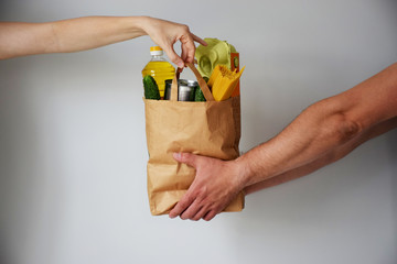 Donation bag with various food. Grocery delivery courier man gives package of food to girl. From...