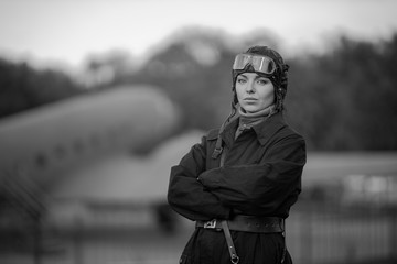 Retro style black and white photography. A young female pilot in uniform of Soviet Army pilots...