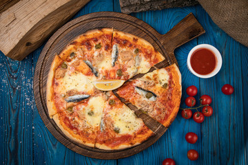 Italian pizza with fish on brown background