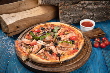 Italian pizza with salmon and olives on blue background