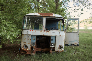 Old abandoned wrecked gray bus in the field. Front side. The driver's seat close-up. Full frame.