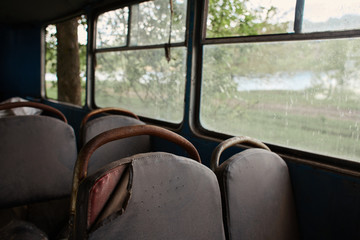 the interior of the destroyed bus close-up, full frame pattern, dirty seats, rusty, window view, creepy view