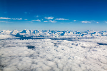 Fototapeta na wymiar Aerial view of Alps mountain range above clouds seen from airplane over Switzerland