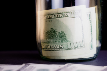 Dollar bills in a glass jar on a black background. Money savings in the jar