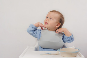 A little boy in a bib sits in a chair