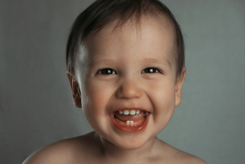 Portrait of a cute laughing little boy on a gray background