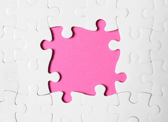 Frame made with white puzzle pieces on pink background, top view. Space for text