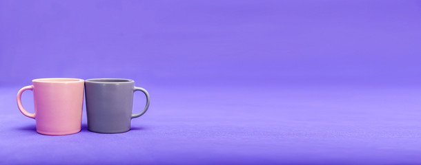 Two beautiful cups of pink and gray are on a purple background. The concept of the holiday - Valentine's Day, Mother's Day, International Women's Day. Place for text. Minimalism with coffee. Breakfast