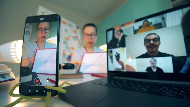 Screens of a smartphone and a laptop during a work video call. Videoconference meeting concept.
