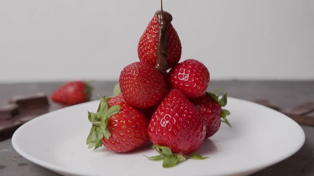 hot melted  chocolate is poured over a fresh ripe strawberries dessert decoration