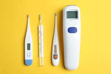 Different thermometers on yellow background, flat lay