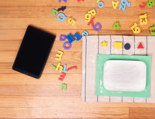 Tablet, colored letters and Flour on floor. Preschool ,
Home school Concept,  Children at home, preschool and kindergarten.