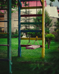 wooden swing on chains in the garden on a background of greenery