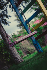 wooden swing on chains in the garden on a background of greenery