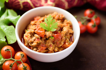 Northern Thai food (Nam Prik Ong), spicy chili minced pork with tomatoes in a bowl eating with vegetables, Thai chili paste