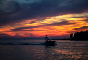 Fototapeta na wymiar sunset over the sea, boat, red, sky, intense, color, clouds, summer, orange, horizon, travel, island, calm, Siesta Key, Florida