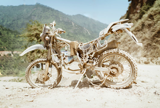 Abandoned old motocross Motorcycle be drowned in deep road dust near the crowed town road in Ramechhap, Nepal.