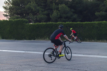 Cyclists ride, dressed up with red and black cloths on country roads on a evening in Spain.