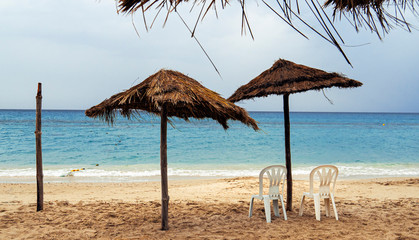 Fototapeta na wymiar Deserted beach with parasols in a resort in Tunisia. The concept of anxiety, loneliness, emptiness and quarantine. Lost rest and summer