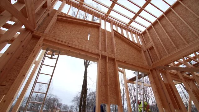 Timelapse from inside of new frame house, view from below of builders covering the house with plywoods. Frame house under construction