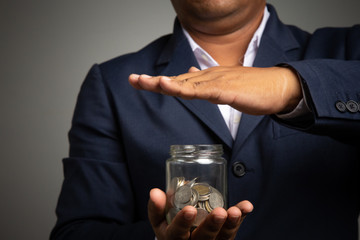 Businessman hand with putting money coins in the office
