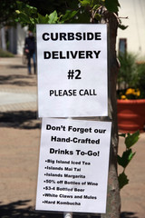 Posters for a curbside pick-up point for drinks and cocktails from a local bar during the coronavirus lockdown and stay at home order in spring of 2020