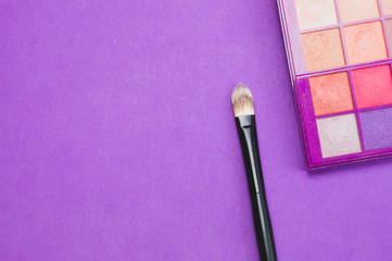 Makeup brushes with powder on purple background. various cosmetic brushes. skin care accessories