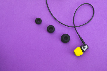 Individuality concept. earphone with yellow ear pad in the end of row of gray embouchures. in-ear headphones. audio equipment