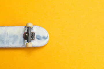 Small skateboard on yellow background. tiny skate for fingers. fingerboard close up © maxkolmeto