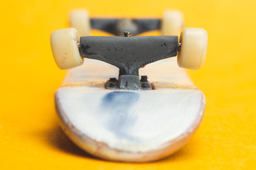 Tiny kateboard on yellow background. small skate for fingers. fingerboard close up