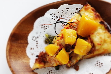 Piece of tropical fruit mango and beef Pizza on wooden plate