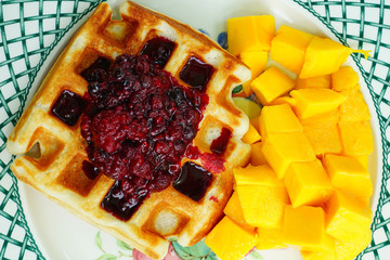 Plate of freshly baked waffles with fresh berry compote for breakfast