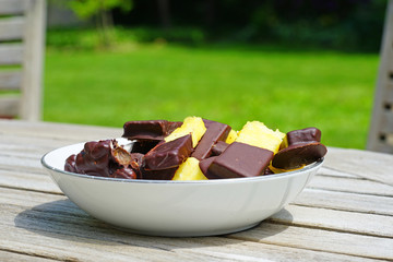 Bowl with fresh pineapple slices dipped in dark chocolate