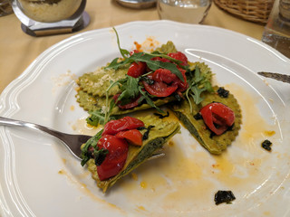 Eating pesto ravioli with tomatoes and arugula in a restaurant