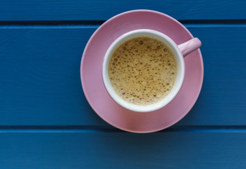 Pink small cup with coffee and macaroon on classic blue wooden table. Nice summer background with  lilac flowers. Spring card template. Good, cozy morning concept. Spring, summer season. Copy space