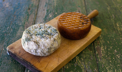 Two cheeses on a wooden board on a rustic table. Smoked cheese and moldy blue cheese.