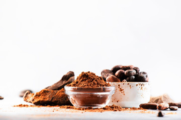 Organic cocoa powder, beans, grated cocoa lump on gray background. Copy space