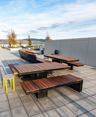 A rooftop deck and alfresco with outside lounge, chairs and tables looking out toward a mountainous...
