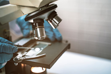 doctor wearing protective gloves using microscope researching corona virus microscopic cells testing vaccination cure, medical center lab china Wuhan world health organization research facilities