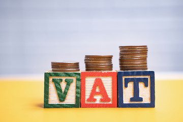 close up value added tax VAT alphabet word block with coins stack on top, representing finance of...