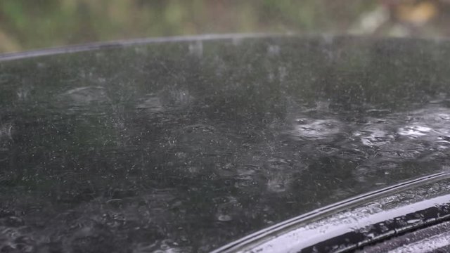 Heavy rain fell on the roof of the car. Driving on rainy days, be careful driving.