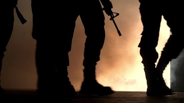 Silhouette group of soldiers walk through smoke , slow motion.