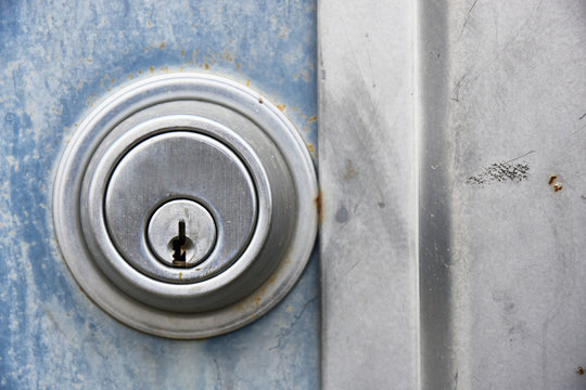A close up image of a old industrial style lock on an exterior metal door. 
