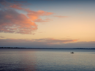 Small Boat at Sea with Dawn Cloudscape