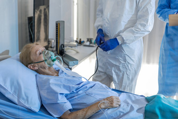 Old female Caucasian patient infected with virus receives oxygen saturation treatment from medical...