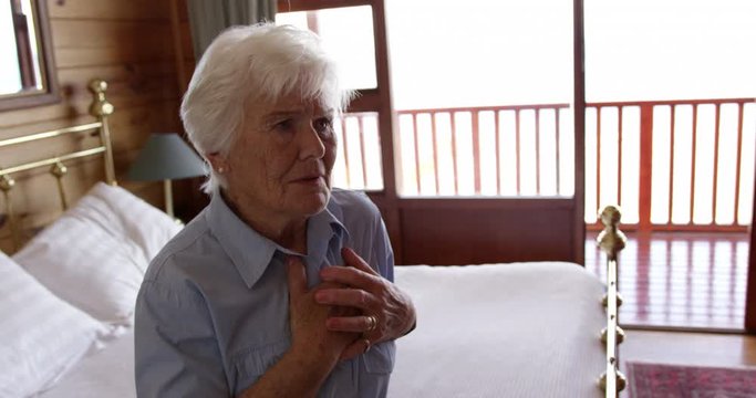 Woman suffering from chest pain in bedroom at home