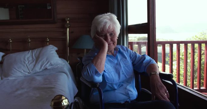 Woman sitting on wheelchair in bedroom at home