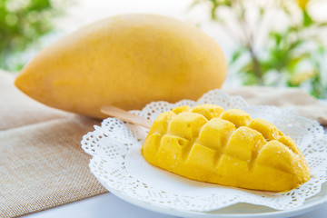 A mango ice cream stick on a white plate with mango fruit on white table background with nature background.